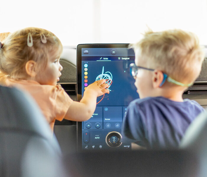 Deux enfants jouent sur la console d'une voiture