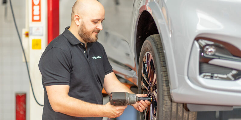 Un mécanicien déboulonne les roues avant d'une voiture