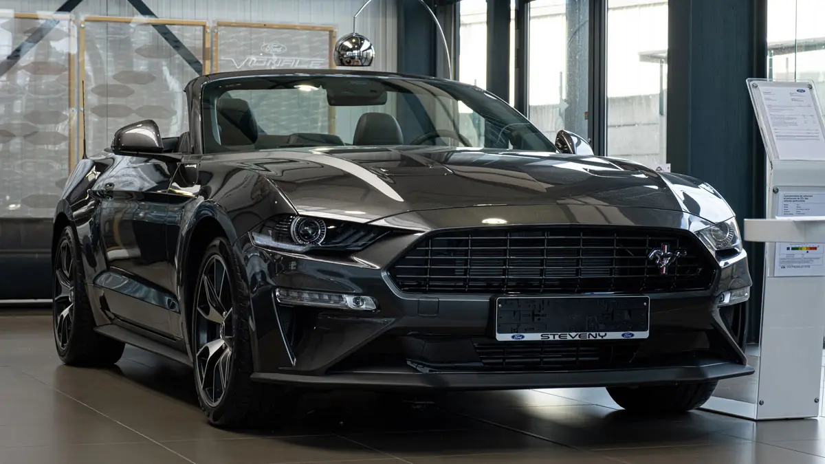 Voiture Ford Mustang noire décapotable exposée dans une concession avec intérieur visible à travers le pare-brise.