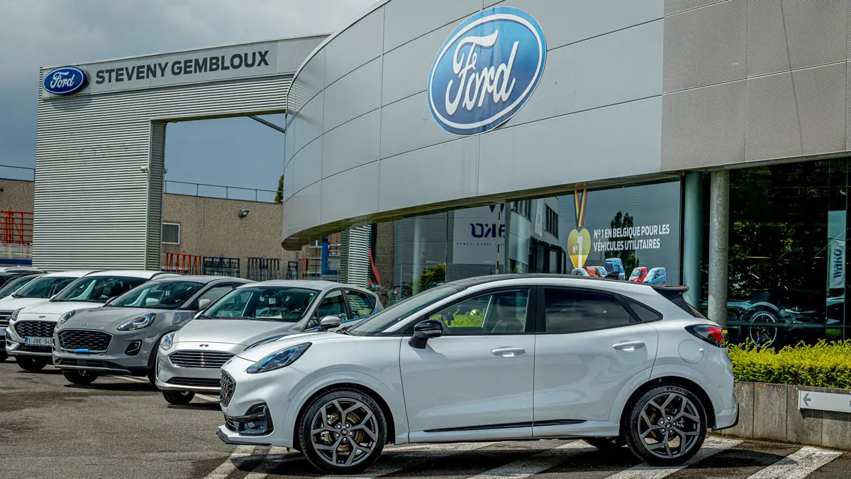 Des voitures Ford blanches garées devant la concession Steveny Gembloux, avec logo Ford visible sur le bâtiment.