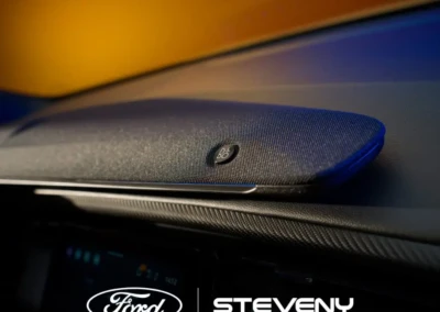 Haut-parleur B&O intégré sur le tableau de bord d'une voiture Ford, avec logos Ford et Steveny visibles.