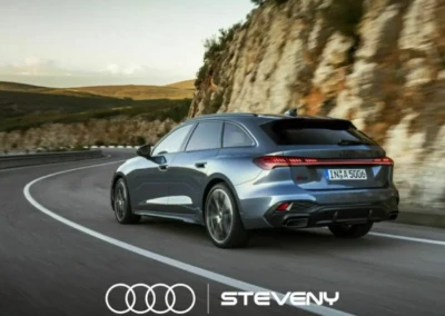 Audi A5 Avant gris roulant sur une route sinueuse bordée de rochers, avec logo Steveny en bas.