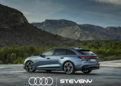 Voiture Audi A5 Avant bleue garée sur un terrain dégagé, avec des montagnes en arrière-plan et le logo Steveny visible.