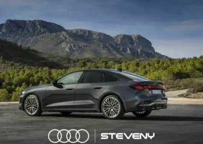 Audi A5 Sedan grise stationnée devant un paysage montagneux, avec le logo Steveny en bas de l'image.