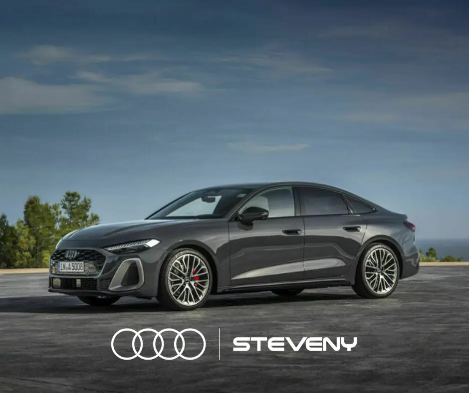 Audi A5 Sedan grise stationnée sur un parking avec des arbres en arrière-plan, logo Steveny au premier plan.