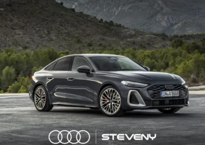 Audi A5 Sedan grise stationnée sur une route devant un paysage montagneux, avec logo Steveny en bas.