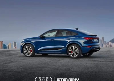 Voiture Audi Q6 Sportback e-tron bleue, vue de profil sur fond urbain avec logo Steveny en bas.