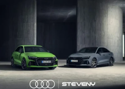 Deux Audi RS3, une verte et une grise, sont garées dans un espace intérieur sombre avec logo Steveny en bas.