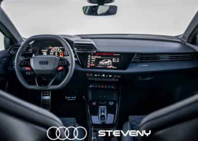 Intérieur de l'Audi RS3 Facelift avec tableau de bord numérique, volant multifonctions et écran central, logo Audi et Steveny visible.