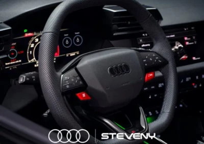 Volant de l'Audi RS3 avec tableau de bord numérique illuminé, logo Audi visible, intérieur moderne et noir.