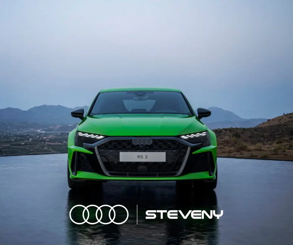 Voiture Audi RS3 verte vue de face, posée sur une surface réfléchissante avec un paysage montagneux en arrière-plan.