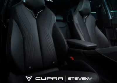 Sièges avant en cuir noir du CUPRA Terramar avec logo CUPRA et accoudoir central, intérieur de voiture sombre.