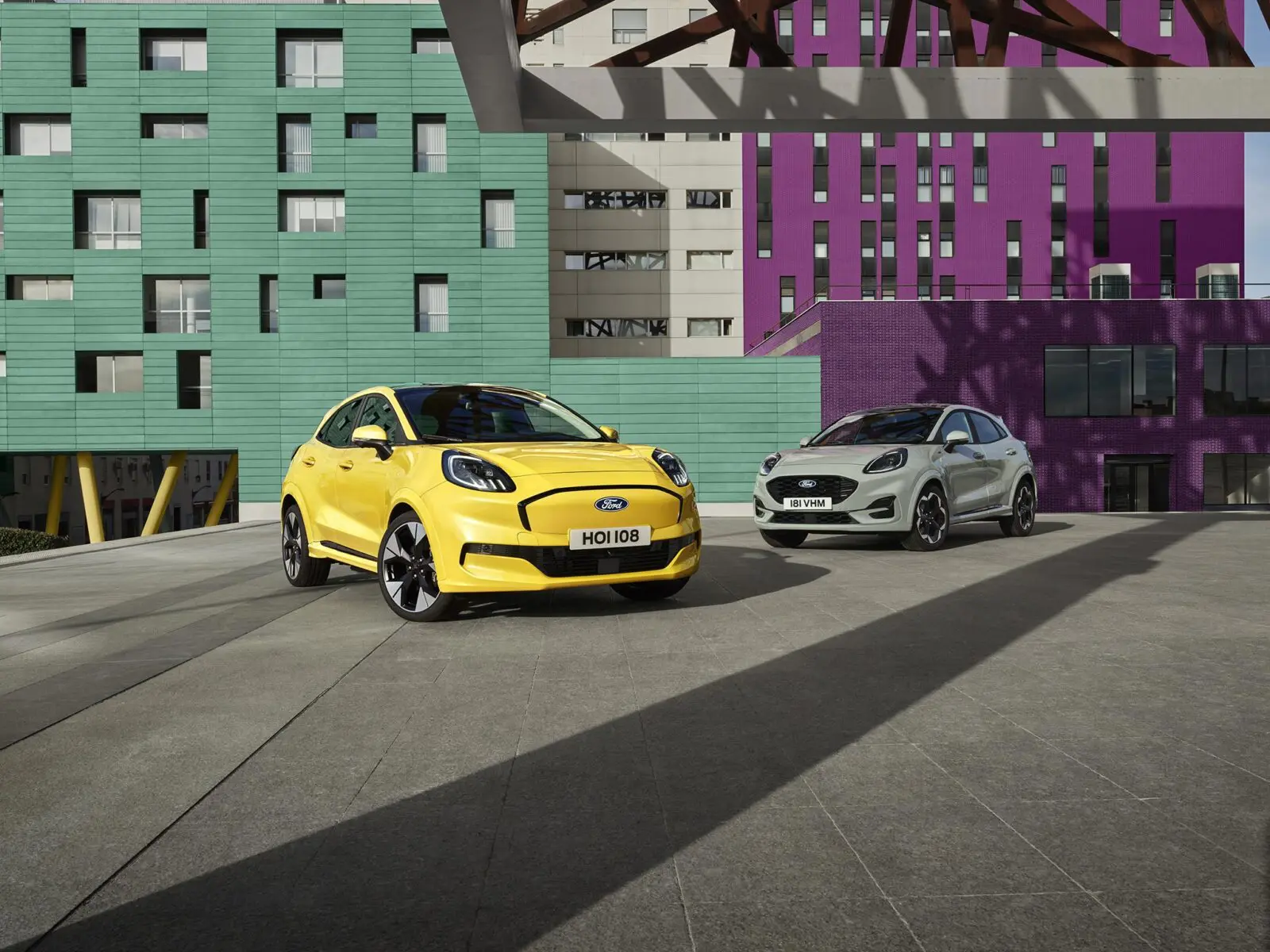 Deux Ford Puma 2024, l'une jaune et l'autre grise, stationnées devant des bâtiments colorés.