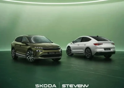 Deux voitures Skoda Enyaq 2025, l'une verte et l'autre blanche, sont exposées dans un espace vert.