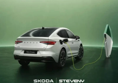 Voiture électrique Skoda Enyaq blanche en charge, connectée à une borne sur fond vert.