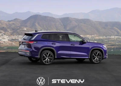 SUV Volkswagen Tayron bleu à sept places garé devant un paysage montagneux, avec logo Steveny au sol.