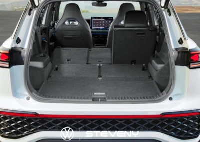 Coffre ouvert d'un Volkswagen Tayron blanc avec sièges arrière rabattus, écran central visible à l'avant.