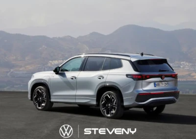 SUV Volkswagen Tayron gris à sept places, garé sur une route avec des montagnes en arrière-plan, logo Steveny en bas.
