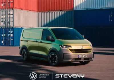 Fourgon Volkswagen Transporter T7 vert stationné devant des conteneurs colorés, avec logos Volkswagen et Steveny visibles en bas.
