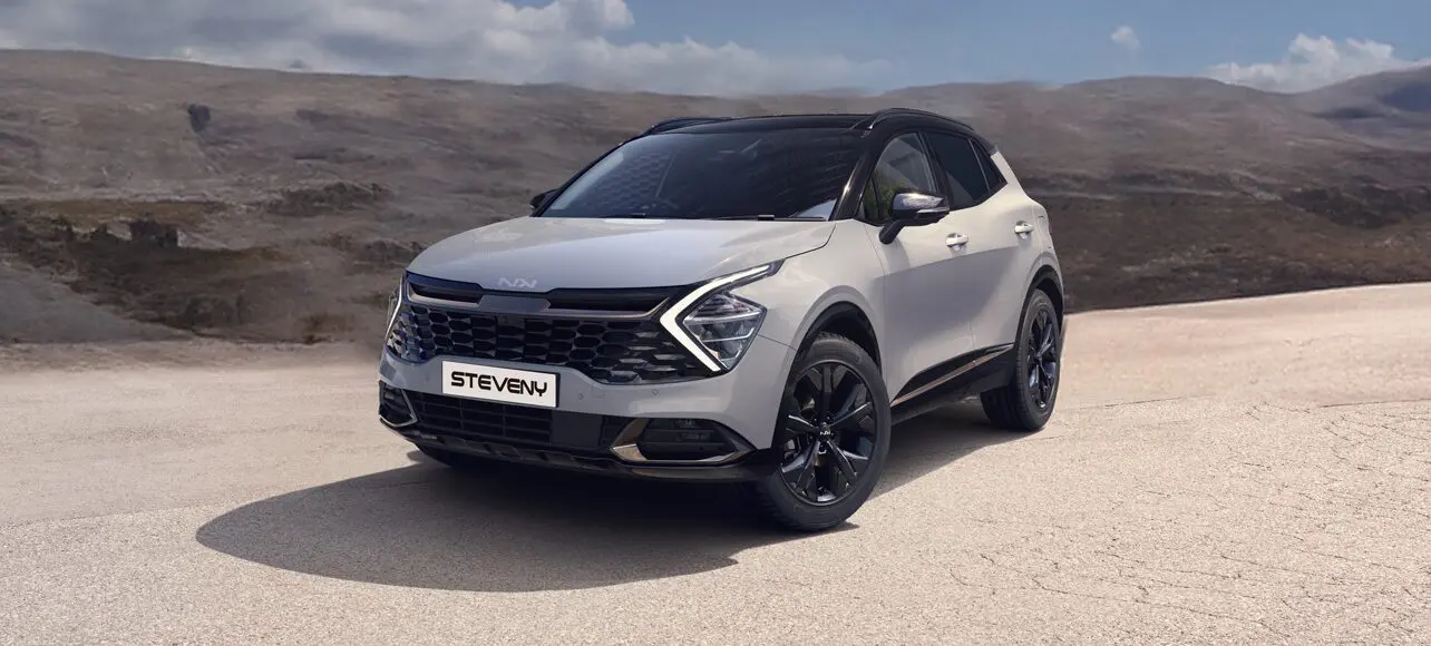 SUV Kia gris sur une route déserte avec un paysage montagneux en arrière-plan, portant une plaque Steveny.