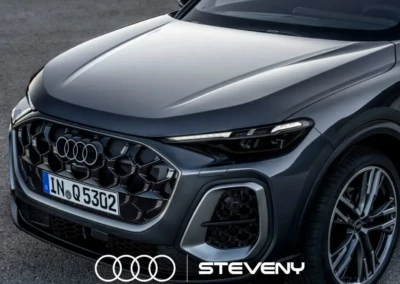 Nouvelle Audi Q5 grise avec calandre hexagonale et logo Steveny, stationnée sur une surface asphaltée.