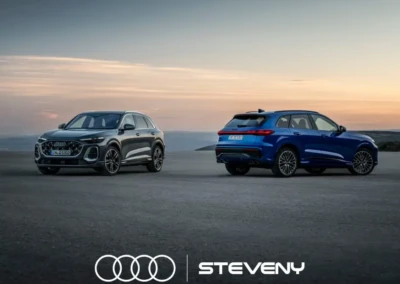 Deux Audi Q5 stationnées sur une route au coucher du soleil, l'une grise et l'autre bleue, avec le logo Steveny.