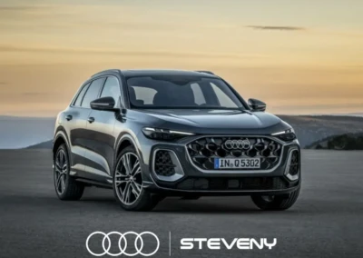 SUV Audi Q5 gris stationné sur une route, avec un logo Steveny en bas, devant un ciel au coucher du soleil.